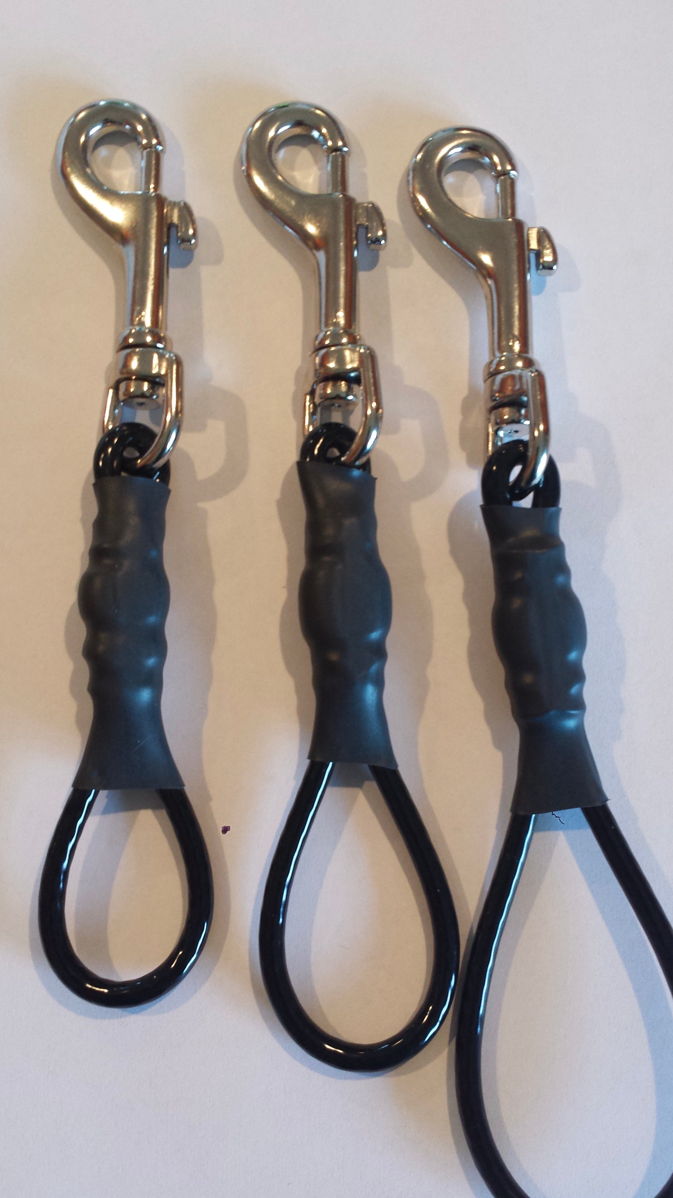 Three black dog leashes with silver clamps on a white background