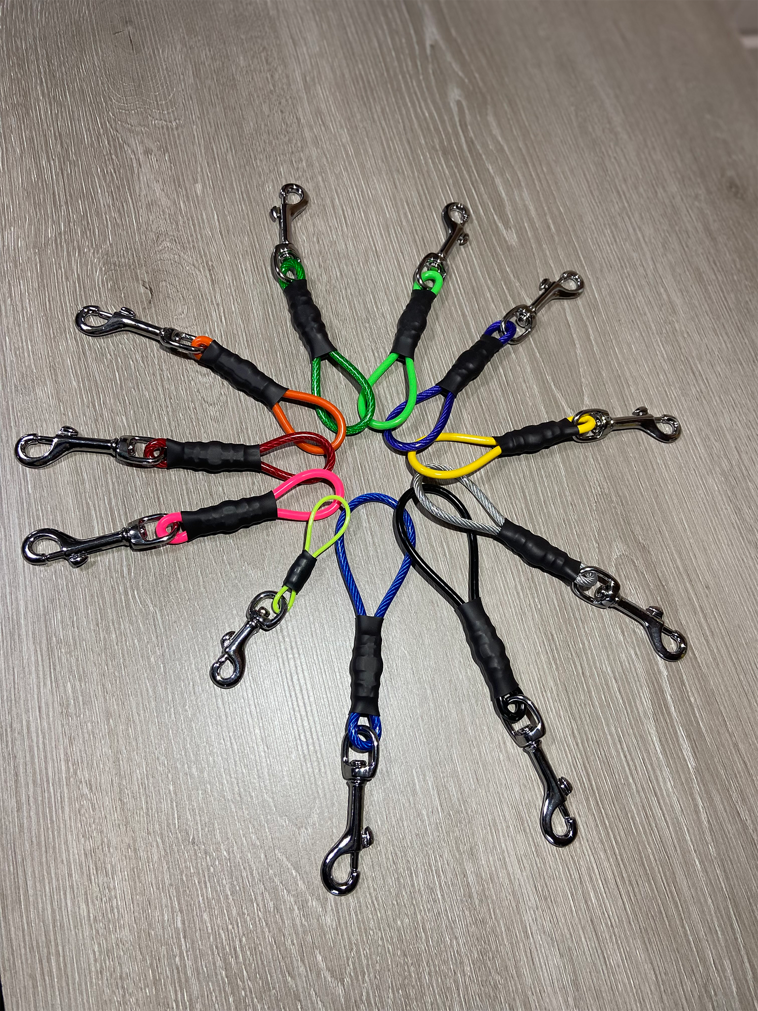 Set of colorful dog leashes with clips arranged in a circular pattern on a wooden surface.