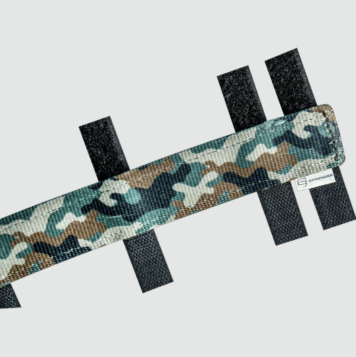 Camouflage-patterned strap with black fasteners on a light gray background